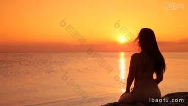 夕阳西下，一个<strong>女人</strong>坐在海滩上的剪影